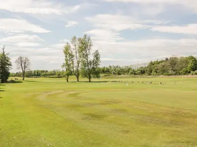 a golf course with trees and a green field at King's Apartment in Castle Douglas