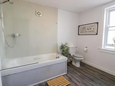 a white bathroom with a tub and a toilet at Fleet Townhouse in Castle Douglas