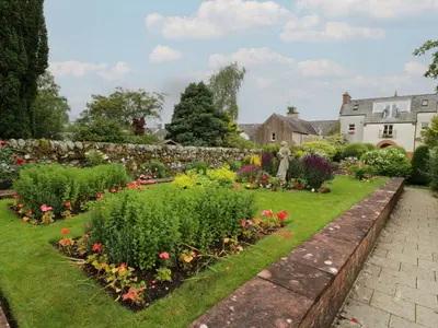 a garden with flowers and a stone wall at Fleet Townhouse in Castle Douglas