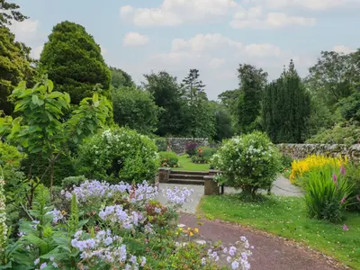 a garden with a bench and many flowers at Fleet Townhouse in Castle Douglas
