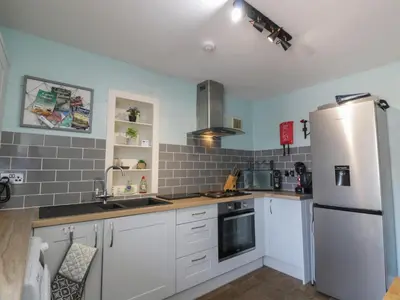 a kitchen with white cabinets and a refrigerator at Fleet Townhouse in Castle Douglas