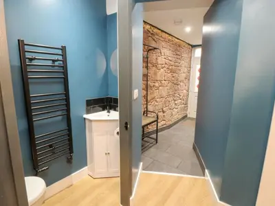 a bathroom with a toilet and a stone wall at 10 Keekle Terrace in Cleator Moor