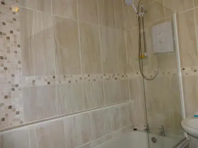 a bathroom with a shower and a tub and a sink at Emilys View, Ireby budget accommodation with fell views in Ireby