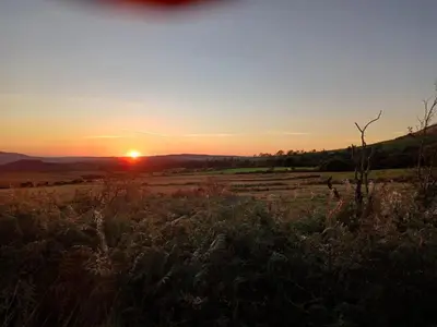 a field with the sunset in the background at Emilys View, Ireby budget accommodation with fell views in Ireby