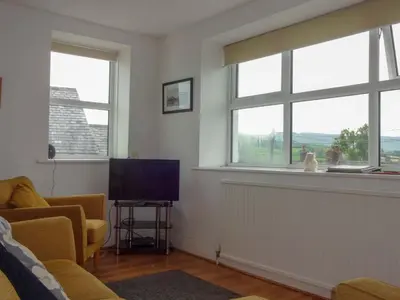 a living room with two windows and a flat screen tv at Emilys View, Ireby budget accommodation with fell views in Ireby