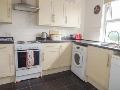 a kitchen with white cabinets and a washer and dryer at Emilys Apartment, Ireby with fell views, ideal budget holiday for a family in Ireby
