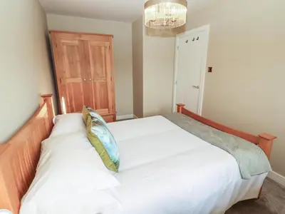 a bedroom with a white bed with a wooden headboard at 3 Hawk Place in Whitehaven