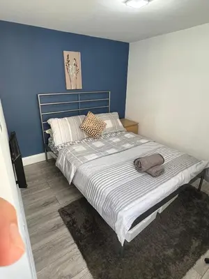 a bedroom with a large bed with a blue wall at Love Shack - Cozy 1BR Walthamstow in Moffat
