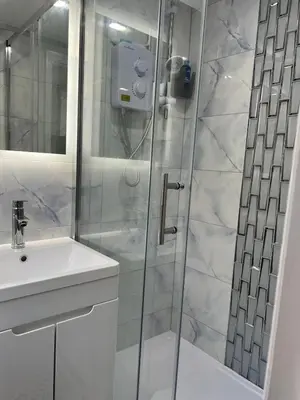 a white bathroom with a shower and a sink at Love Shack - Cozy 1BR Walthamstow in Moffat