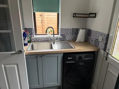 a kitchen with a sink and a washing machine at 2 bedroom cottage in Ayr