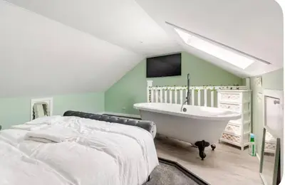 a bedroom with a bed and a bath tub at 2 bedroom cottage in Ayr