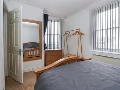 a bedroom with a bed and a dresser and windows at Duncan Square in Whitehaven