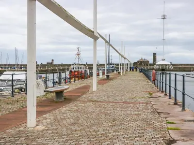a pier with a bench and a boat in the water at Duncan Square in Whitehaven