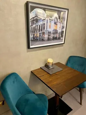 a table with two blue chairs and a picture of a building at Elegant Chelsea Apartment in Moffat