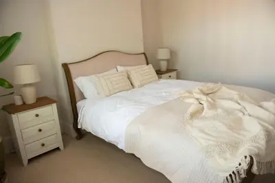 a bedroom with a white bed and two night stands at Wimbledon Tennis House in Moffat