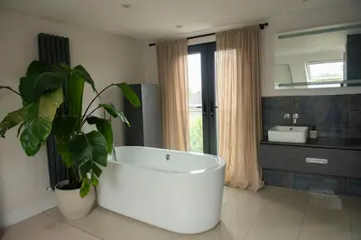 a bathroom with a large white tub and a plant at Wimbledon Tennis House in Moffat