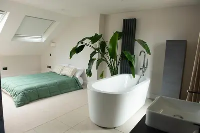 a bathroom with a large plant and a bath tub at Wimbledon Tennis House in Moffat
