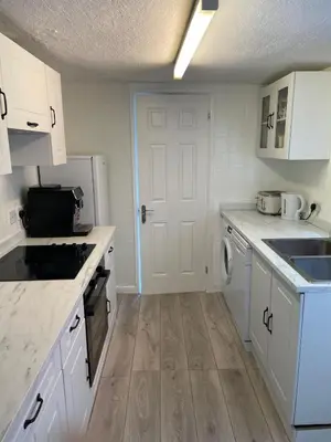 a kitchen with white cabinets and a white door at Home in Reading Uni Area in Moffat