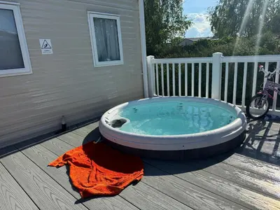 a hot tub sitting on a deck next to a house at Tattershall caravan with private hot tub in Moffat