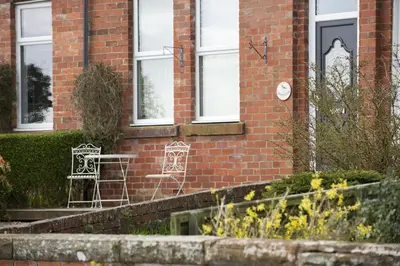 a brick building with two chairs in front of it at Shoreside in Powfoot