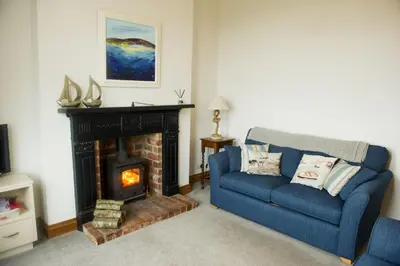 a living room with a blue couch and a fireplace at Shoreside in Powfoot