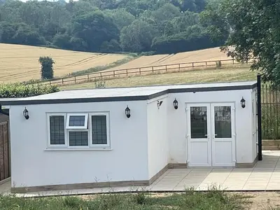a small white shed with a door and a field at Detached Annexe in Moffat
