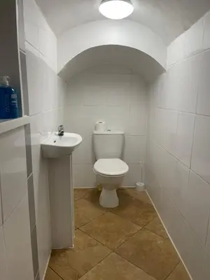 a white bathroom with a toilet and a sink at First Avenue Apartments in Moffat