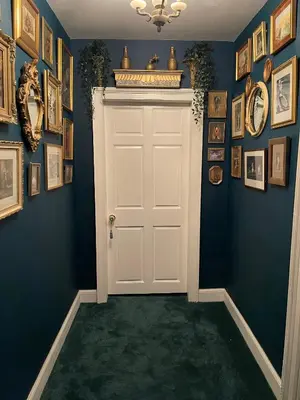 a hallway with a white door and a bunch of pictures at Craigielands House in Beattock
