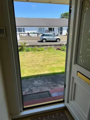 a door with a view of a car in a parking lot at 2 bedroom Lake district cottage in Cockermouth