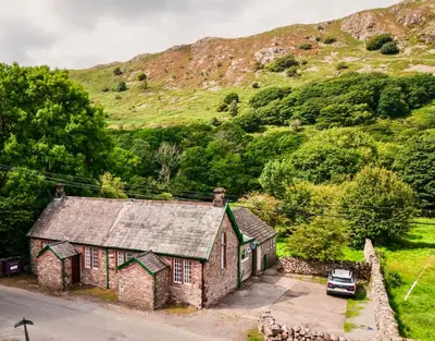 an old stone house with a car parked in front at The Old School House - Eskdale in Holmrook