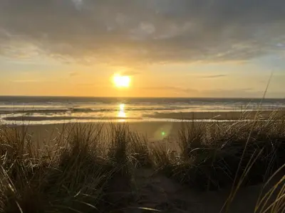 a sunset on a beach with the ocean in the background at The Old School House - Eskdale in Holmrook