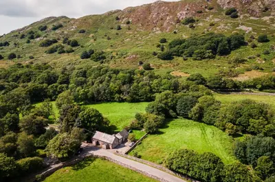 an aerial view of an old house in the middle of a mountain at The Old School House - Eskdale in Holmrook
