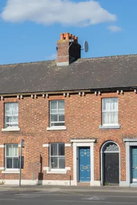 a brick building with a blue door and a chimney at Saint Nico in Carlisle
