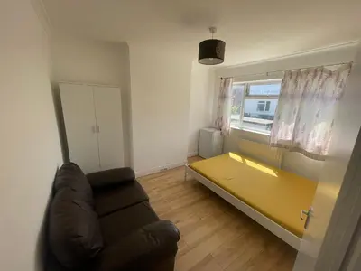 a living room with a couch and a yellow table at Large room with bathroom in Moffat