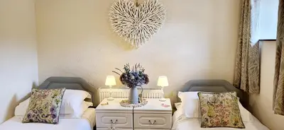 a bedroom with two beds and a table with a vase at Ash Lodge at The Barn in Gosforth