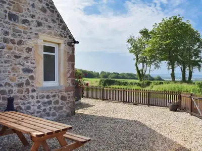 a wooden bench outside of a stone building with a fence at High Wardneuk - Uk47041 in Symington