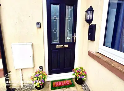 a black door with some flowers on the steps at 12 Seacote Garden by Prestige Properties SA in St Bees