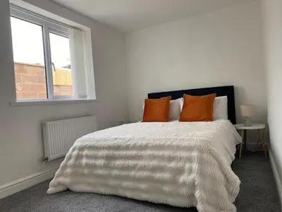 a bedroom with a bed with orange pillows and a window at Modern 2Bed Garden Apartment in Heart of Penarth in Moffat