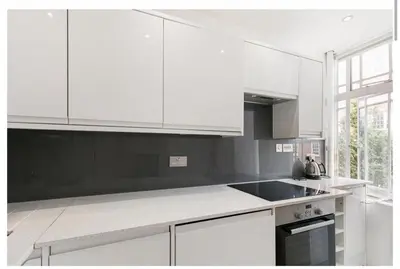 a kitchen with white cabinets and a black counter top at 2 Bedroom Apartment Queensway in Moffat