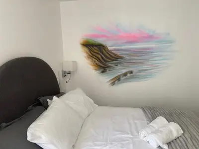 a bedroom with a bed with a painting on the wall at Serenity Suites in Douglas