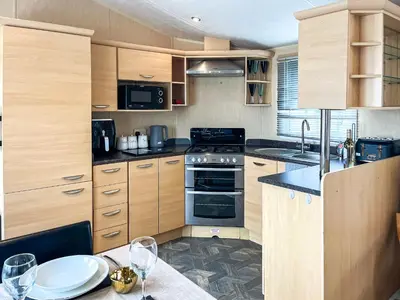 a kitchen with wooden cabinets and a table with wine glasses at Keswick Reach in Cockermouth