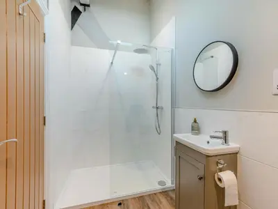 a bathroom with a shower with a sink and a mirror at Tower Cottage in Glenridding