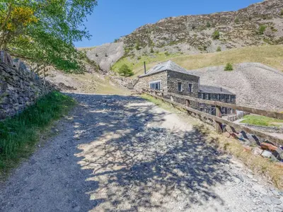 a dirt road next to a building on a hill at Tower Cottage in Glenridding