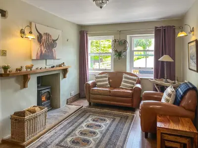 a living room with a couch and a fireplace at Gillhead Farm Cottage in Troutbeck