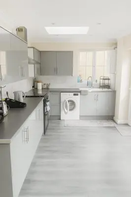 a kitchen with white cabinets and a washing machine at Nayla house in Moffat