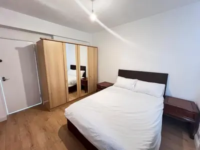 a bedroom with a white bed and a wooden cabinet at Flat in London Bridge in Moffat