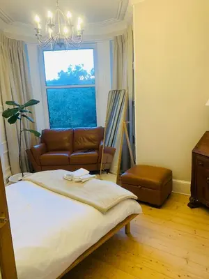 a bedroom with a bed and a couch and a window at Rachael's House in Moffat