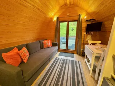 a living room with a gray couch in a wooden room at Queensland Holiday Park - Glamping in South West Scotland in Barrhill