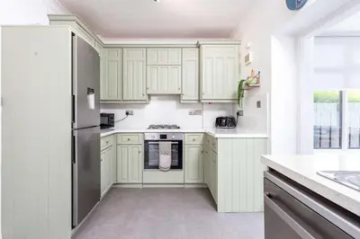 a kitchen with white cabinets and a stainless steel refrigerator at No15 Ellis House - Donnini Apartments in Kilmarnock