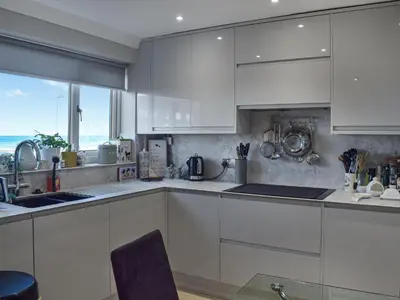a white kitchen with white cabinets and a window at Bay View in Maidens